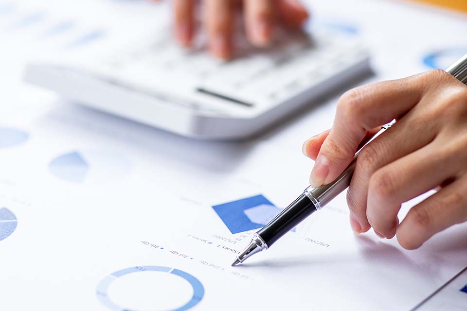 Close up Business woman using calculator and laptop for do math finance on wooden desk, tax, accounting, statistics and analytical research report concept