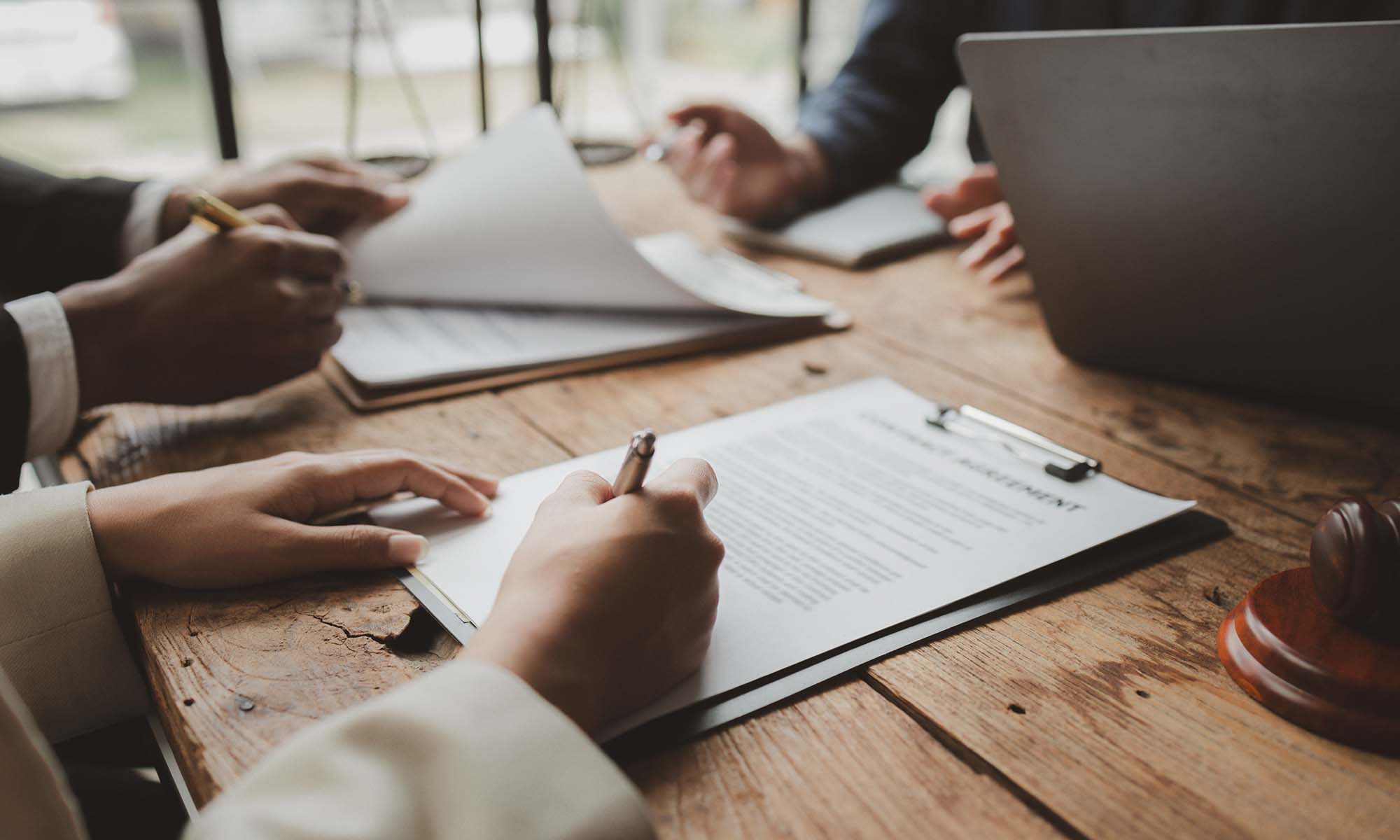 Business people negotiating a contract, discussing contract while working together in sunny modern office, unknown businessman and woman with colleagues or lawyers at meeting.