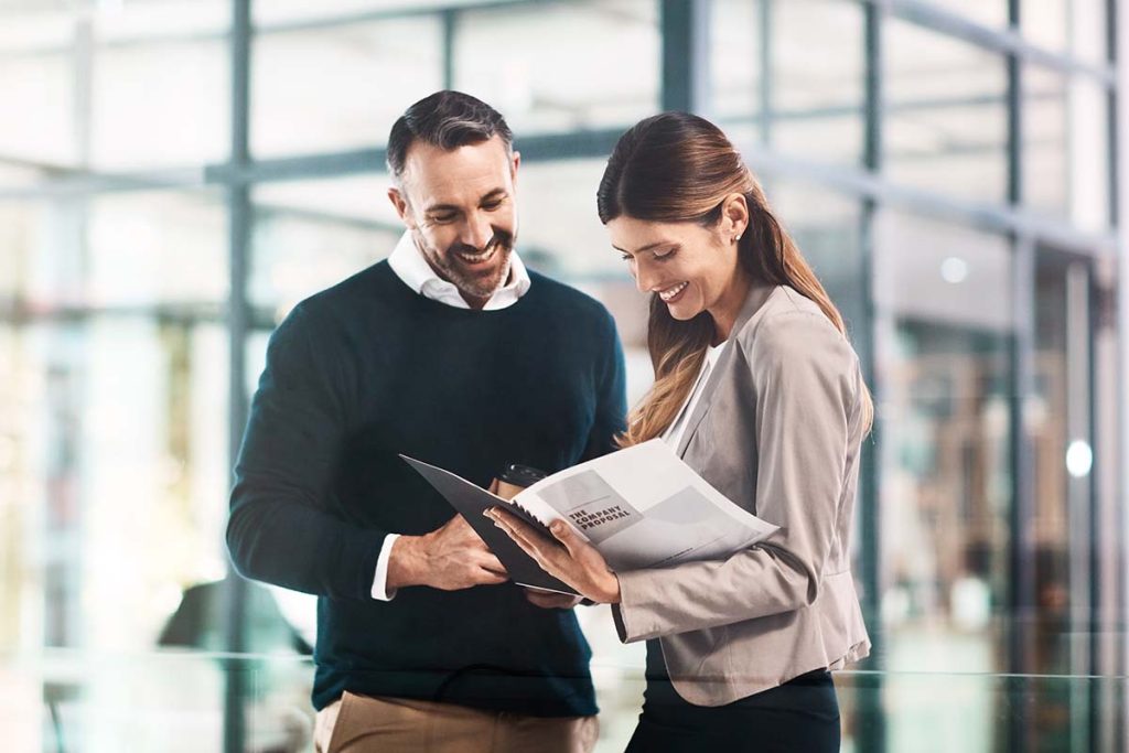 Man, woman and paperwork for company proposal in office for funding, reading or review for project. Business people, partner and investor with feedback, compliance and happy for results in workplace